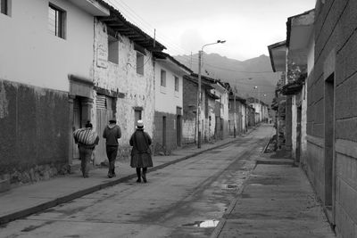 Rear view of people walking on road amidst buildings