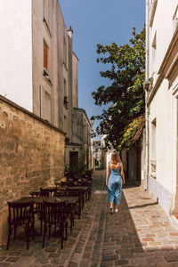 Rear view of woman walking on street amidst buildings