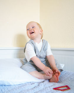 Cute baby girl sitting on bed at home