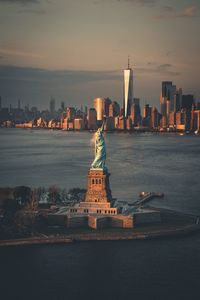 Statue of liberty in city against sky