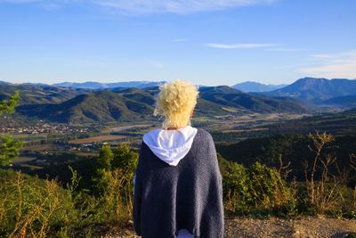 Rear view of man looking at mountains against sky