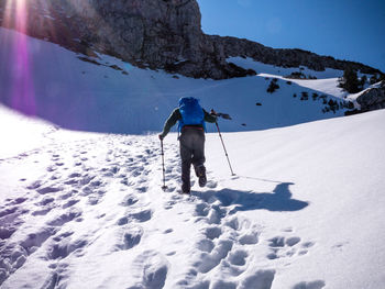 Rear view of person hiking on snow covered mountain