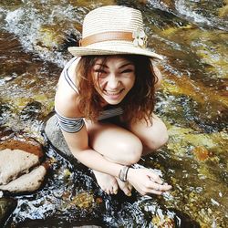Portrait of smiling young woman on rock in river