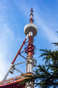 Low angle view of communications tower against cloudy sky