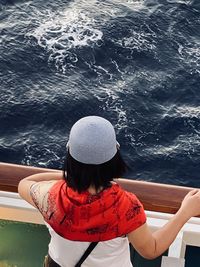 Rear view of woman in hat by sea