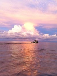 Boats sailing in sea against cloudy sky