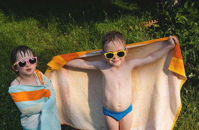 Wet happy children in sunglasses in a towel. summer is a time of pleasure and fun