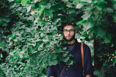 Portrait of young man standing against plants