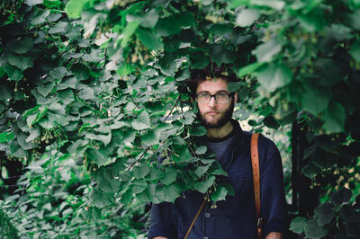 Portrait of young man standing against plants