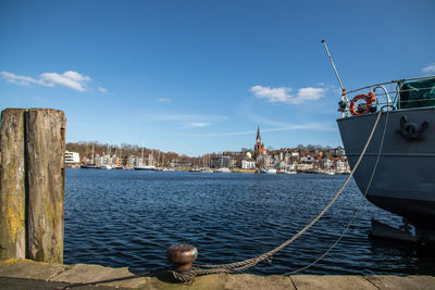Sailboats moored at harbor against sky