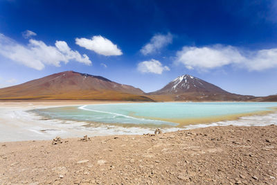 Scenic view of beach and mountains against blue sky