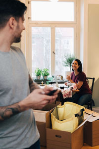 Smiling woman sitting at table with man standing in foreground