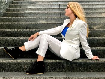 Side view of young woman sitting on staircase