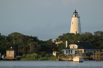 Lighthouse by building against sky