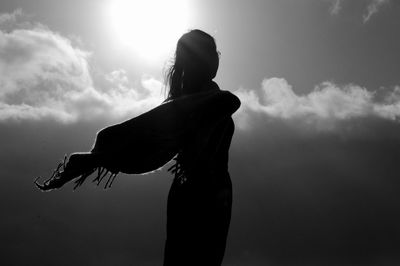 Side view of silhouette woman standing against sky on sunny day