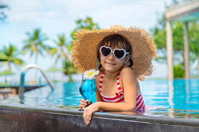 Portrait of girl wearing sunglasses while swimming in pool