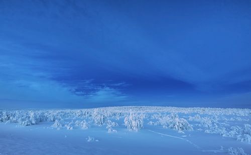 Aerial view of snowcapped landscape against blue sky