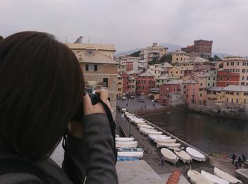 Rear view of woman sitting against buildings in city