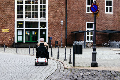Rear view of man riding toy car on city street