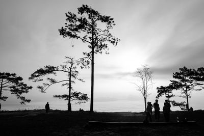 Silhouette people standing by tree on field against sky