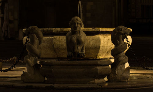 Statue of man and woman sitting by building