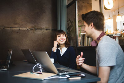 Smiling female professional looking at male colleague while planning strategy during meeting at office