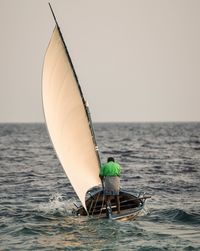 Rear view of man in fishing boat on sea against sky