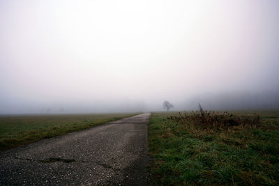 Road amidst field against sky