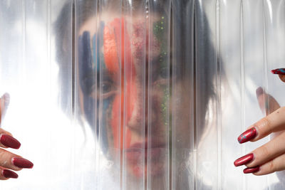 Close-up portrait of woman with painted face seen through plastic