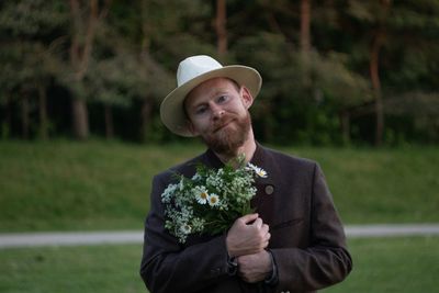 Portrait of man wearing hat standing against plants