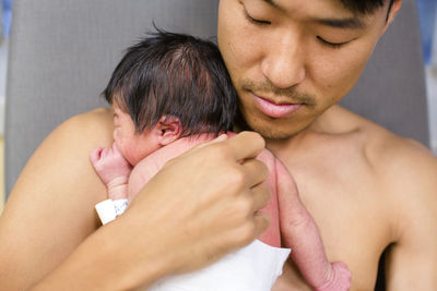 A new father rests peacefully skin-to-skin with his newborn baby girl