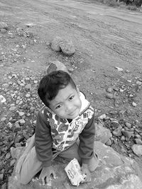 High angle portrait of boy sitting on rock