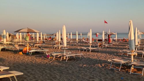 Lounge chairs and parasols on beach against sky