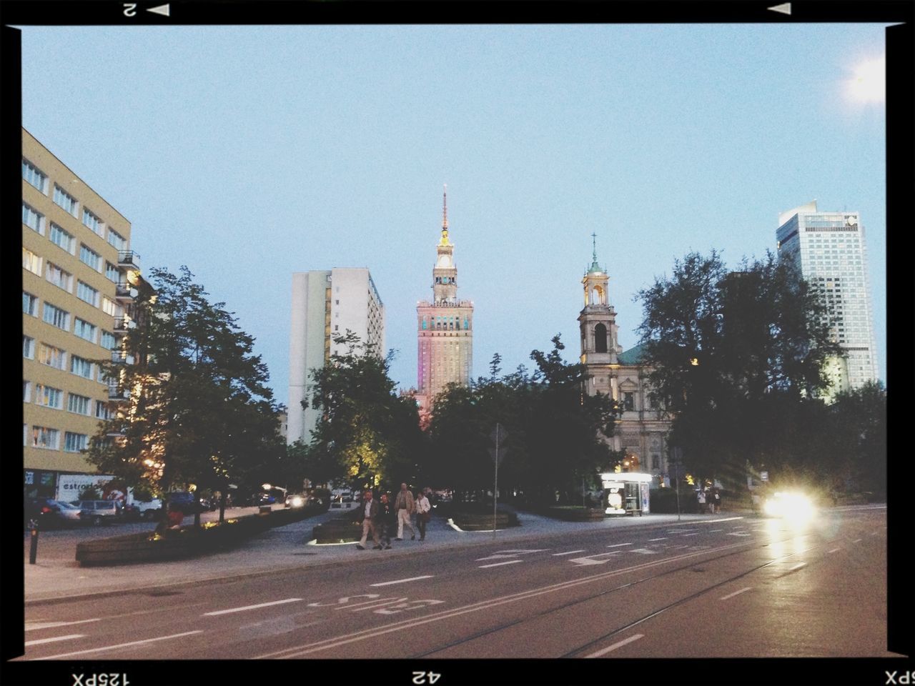 building exterior, architecture, built structure, transfer print, city, clear sky, auto post production filter, transportation, car, street, road, city street, land vehicle, tower, city life, sky, travel, travel destinations, road marking, capital cities