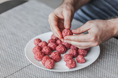 High angle view of hand holding strawberries on table