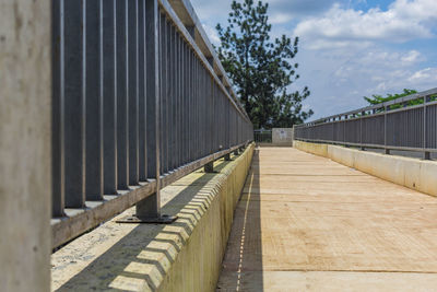 Walkway by bridge against sky