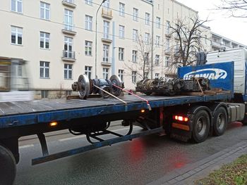 Side view of vehicles on road against buildings