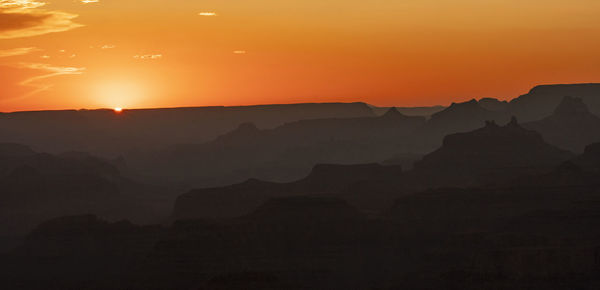 Scenic view of silhouette mountains against orange sky