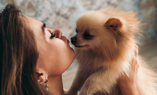 Cute young brunette girl kisses her pomeranian spitz dog. the concept of home comfort and pet care