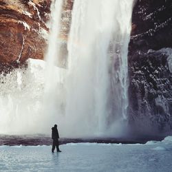 Rear view of man standing against waterfall