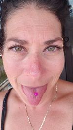 Close-up portrait of woman showing candy while sticking out tongue