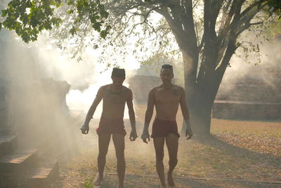 Rear view of people walking on street amidst trees