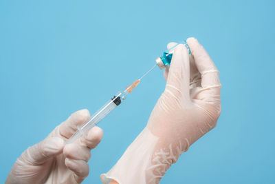 Midsection of person holding hands against blue background