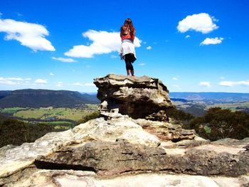 Woman standing on rock against sky