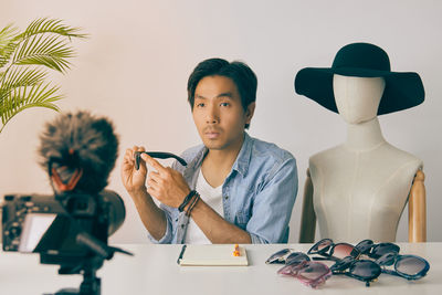Portrait of young man looking away while sitting on table