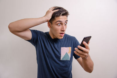 Young man using smart phone against white background