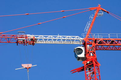 Low angle view of crane against clear blue sky