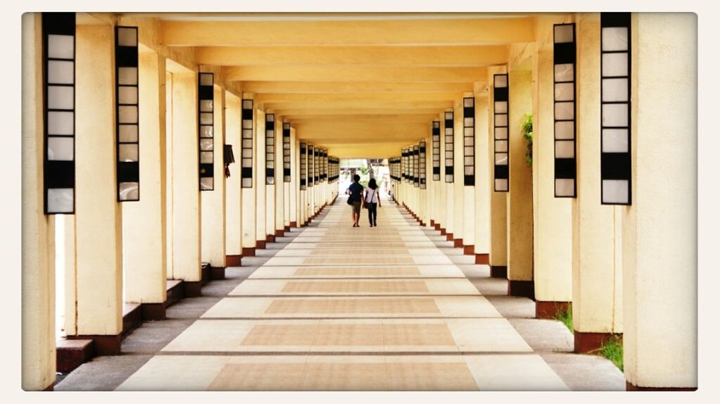 REAR VIEW OF WOMAN WALKING IN CORRIDOR OF PEOPLE