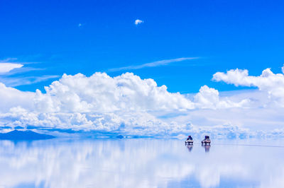 Cars on salt lake against sky