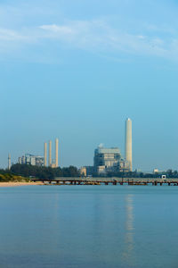 Sea and buildings in city against sky